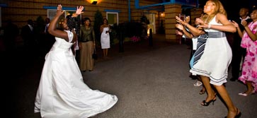 Night time scene: Bride throws her bouquet to anticipating guests.

